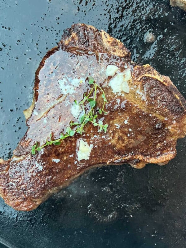 porterhouse steak on blackstone griddle with garlic butter and thyme.