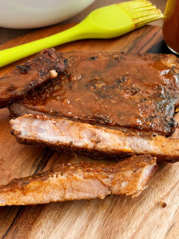 electric smoker smoked ribs with bbq sauce on cutting board.