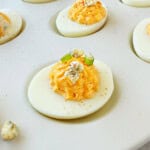 Buffalo deviled eggs topped with paprika, chives and gorgonzola.