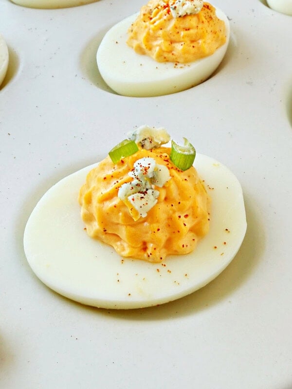 Buffalo deviled eggs topped with paprika, chives and gorgonzola.