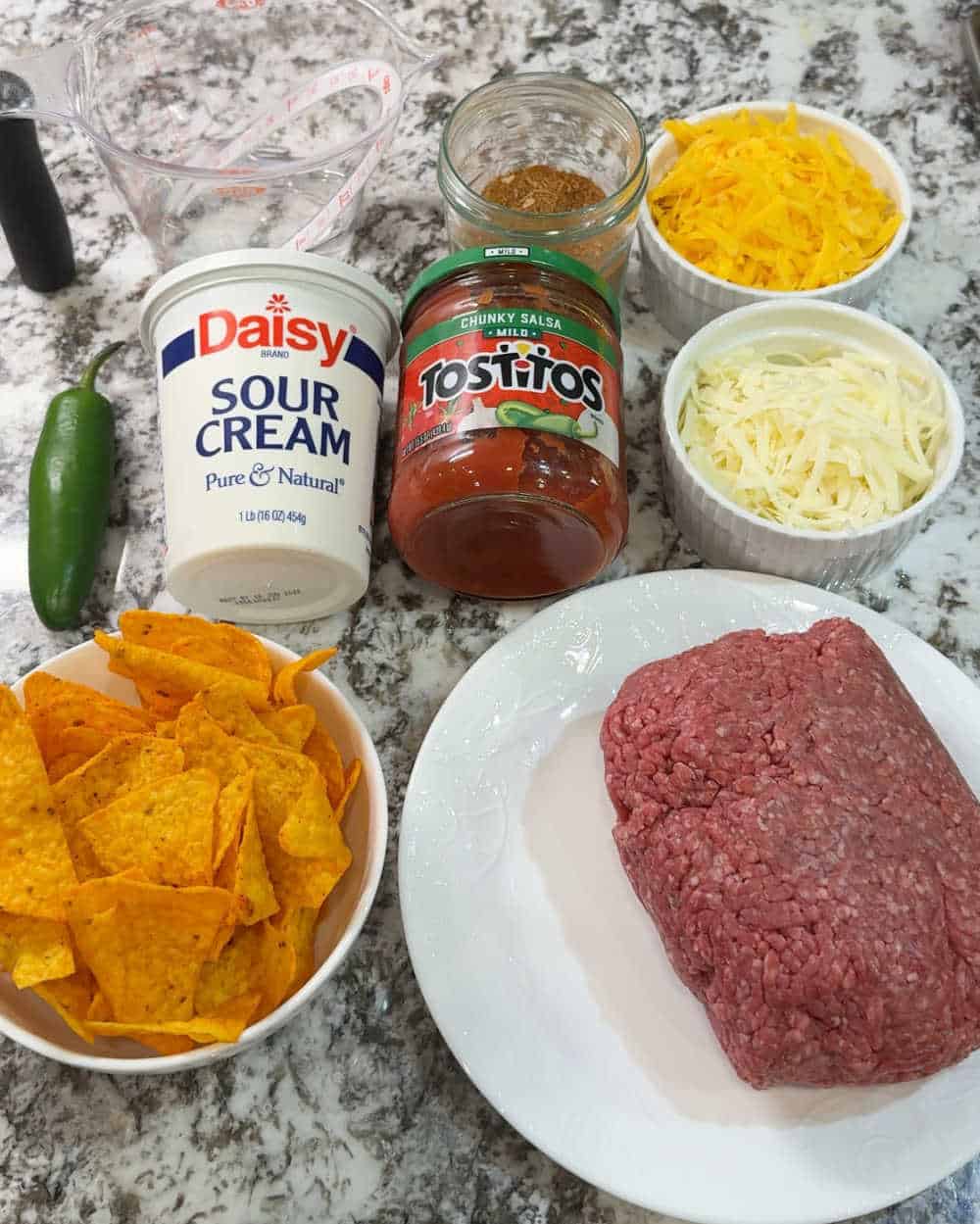 ground beef, Doritos, cheese, salsa, seasoning, sour cream and jalapeno.