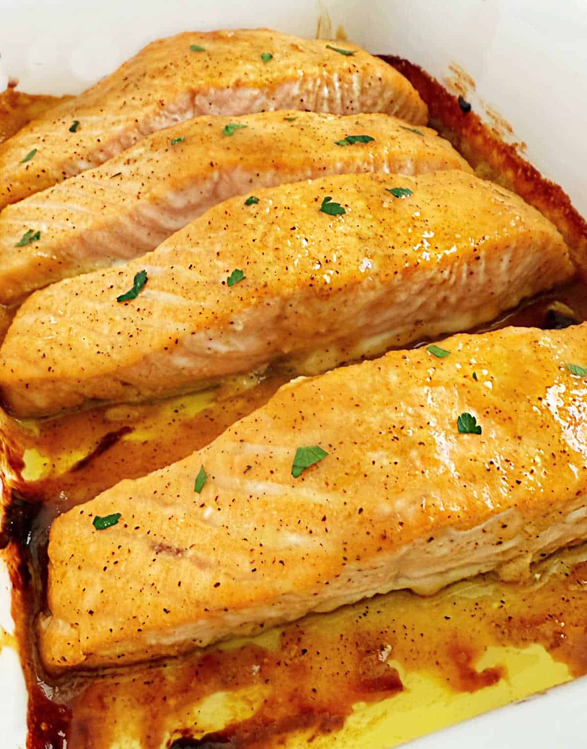 baked honey mustard salmon fillets with parsley in casserole dish.
