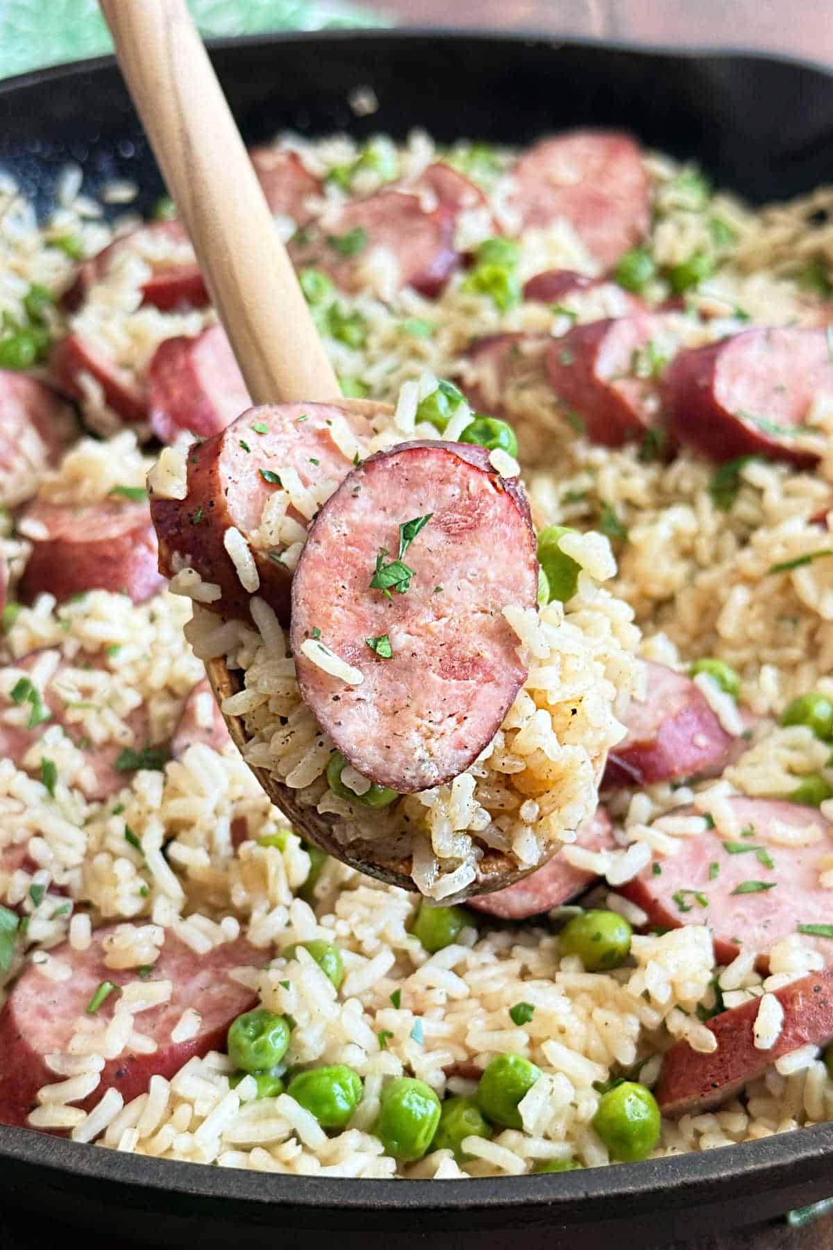 kielbasa and rice on wooden spoon over skillet.