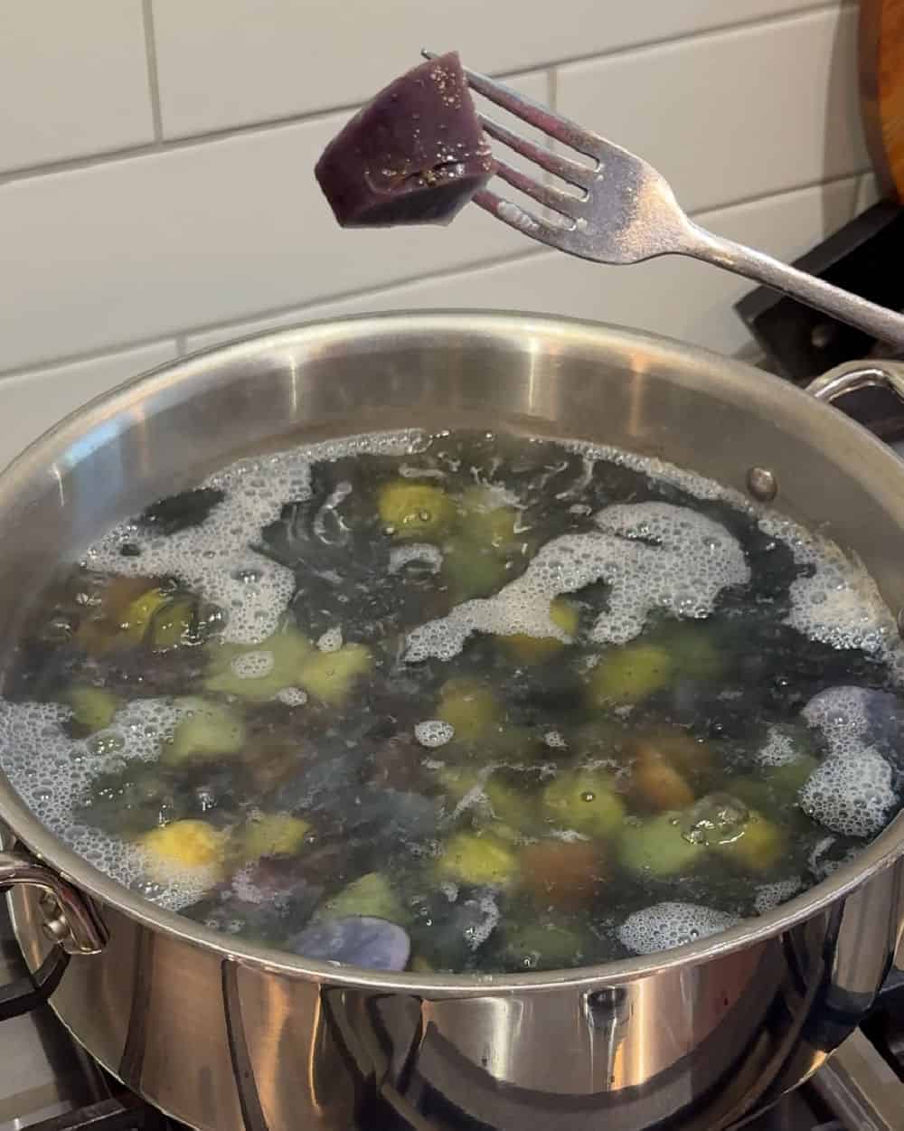 boiled purple potato on fork.