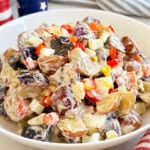 red, white and blue potato salad with red peppers in serving bowl.