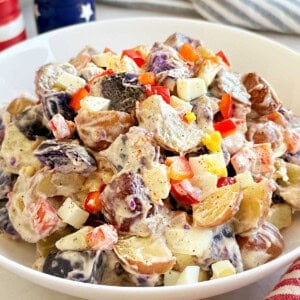 red, white and blue potato salad with red peppers in serving bowl.
