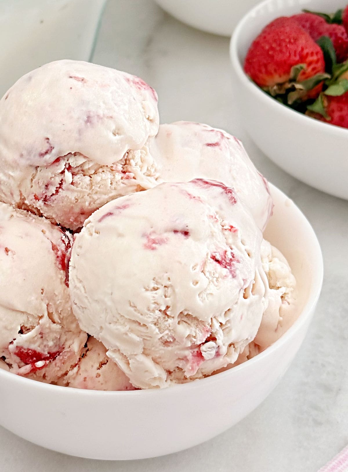 scoops of no churn strawberry ice cream in bowl.