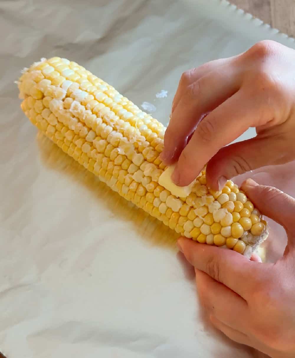spreading corn cob with butter.