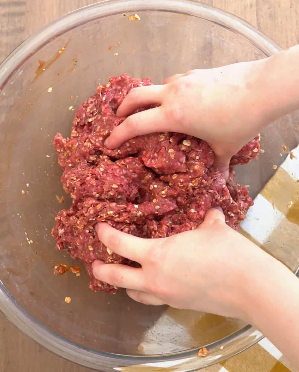 hands mixing meat mixture.