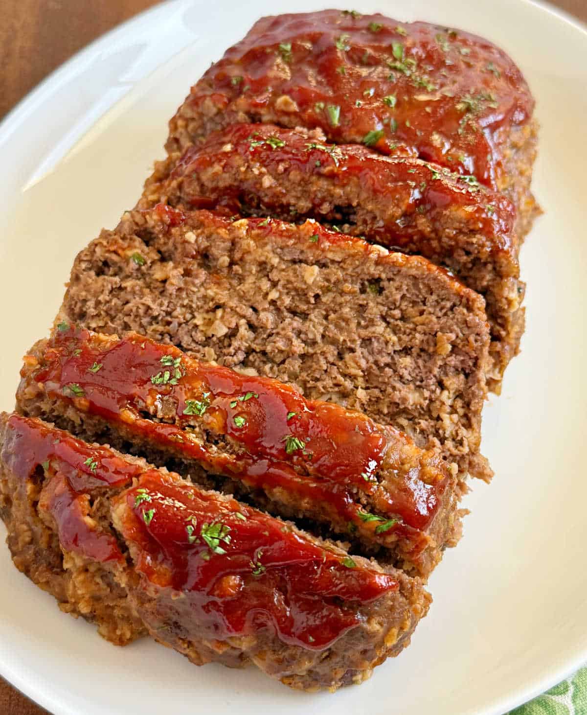 sliced slow cooker meatloaf on a white platter.