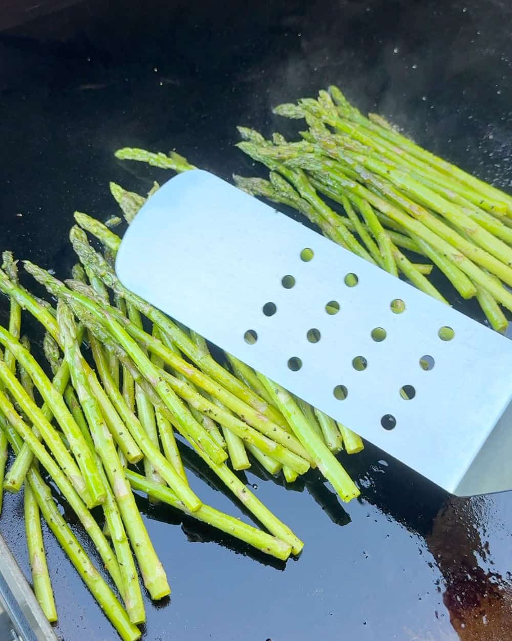 stir asparagus with grilling spatula.