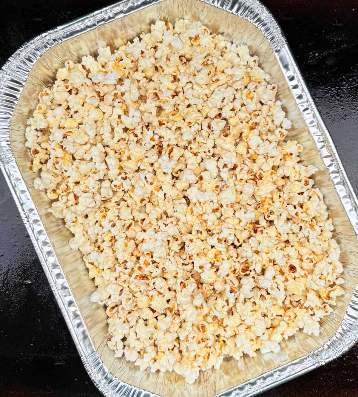 Blackstone popcorn in foil pan on griddle.