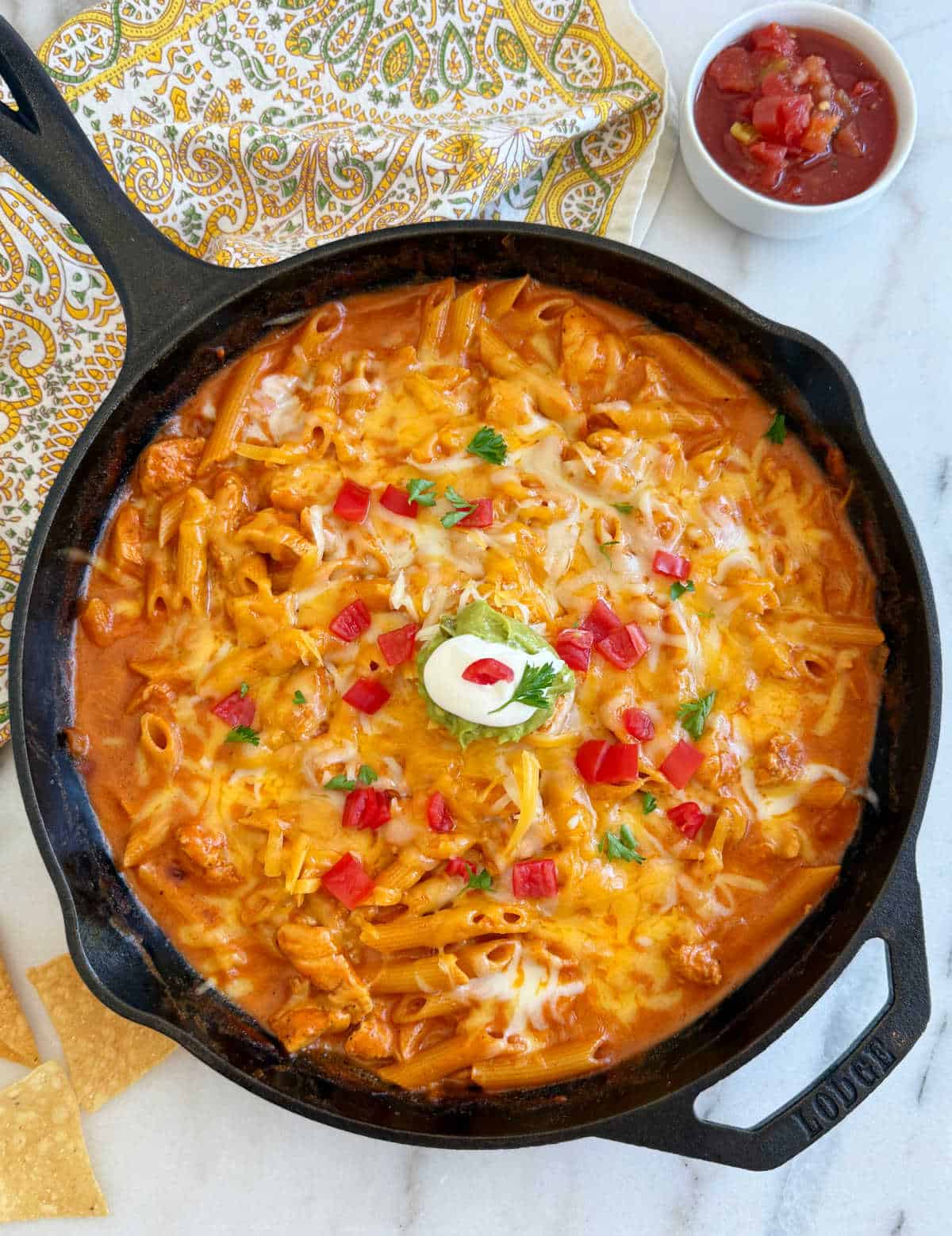 skillet with chicken enchilada pasta and toppings.
