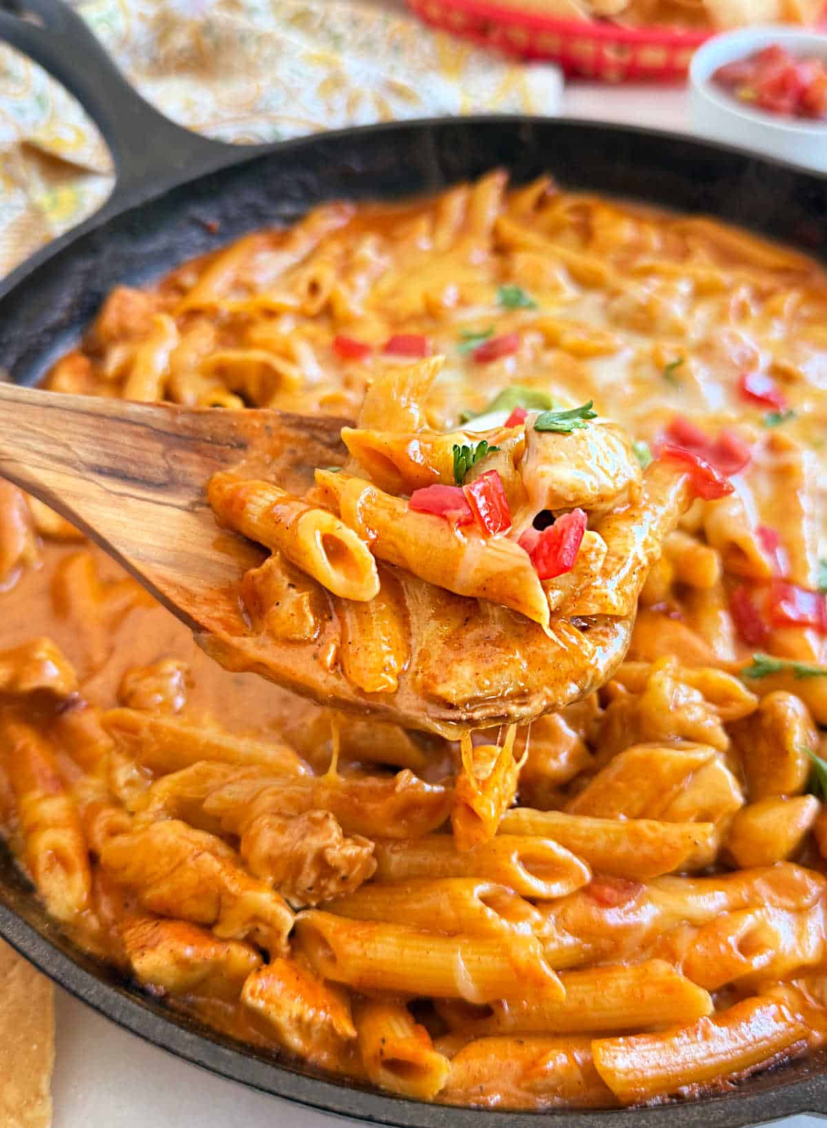 chicken with penne pasta and creamy enchilada sauce on serving spoon.
