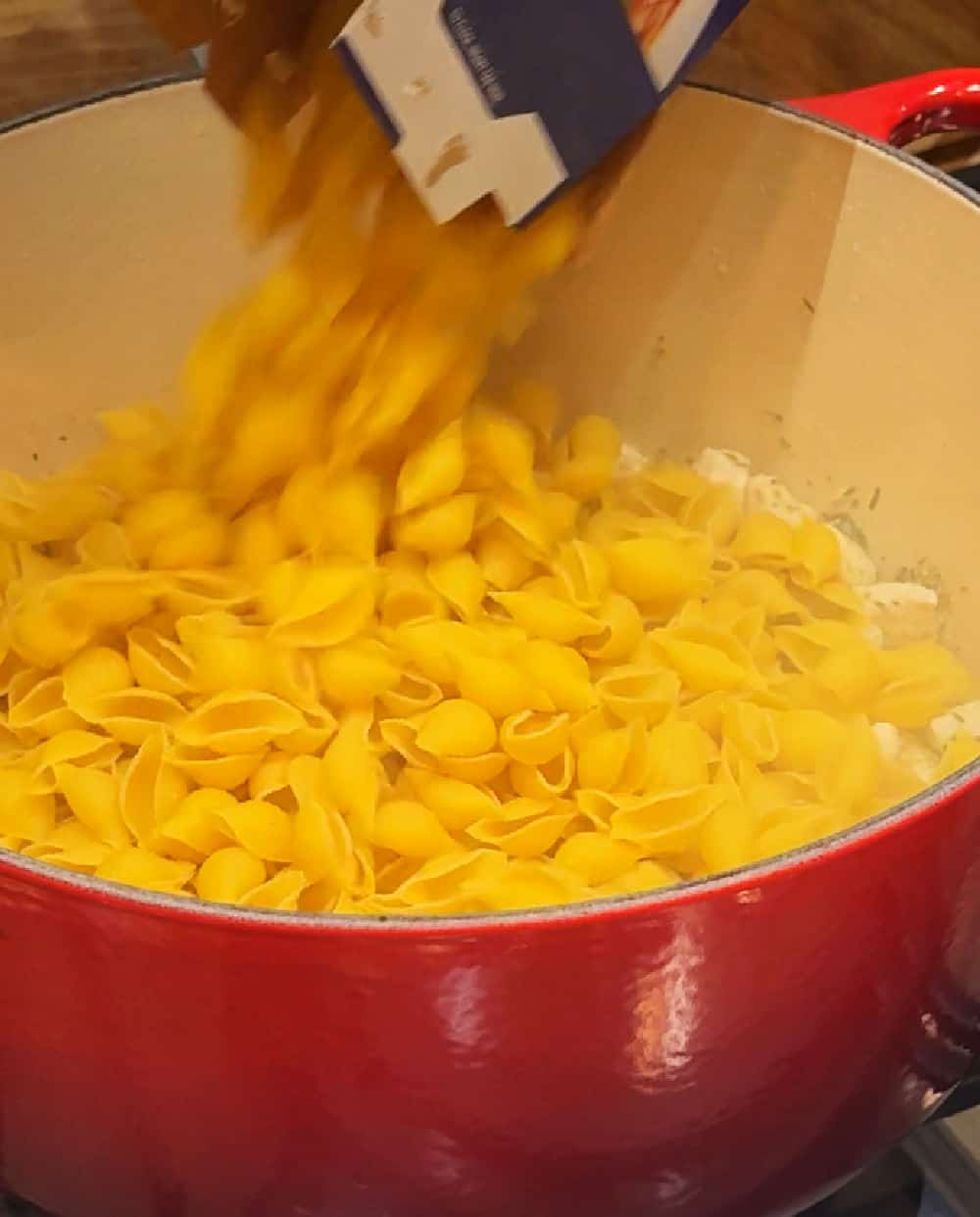 pouring pasta into dutch oven.