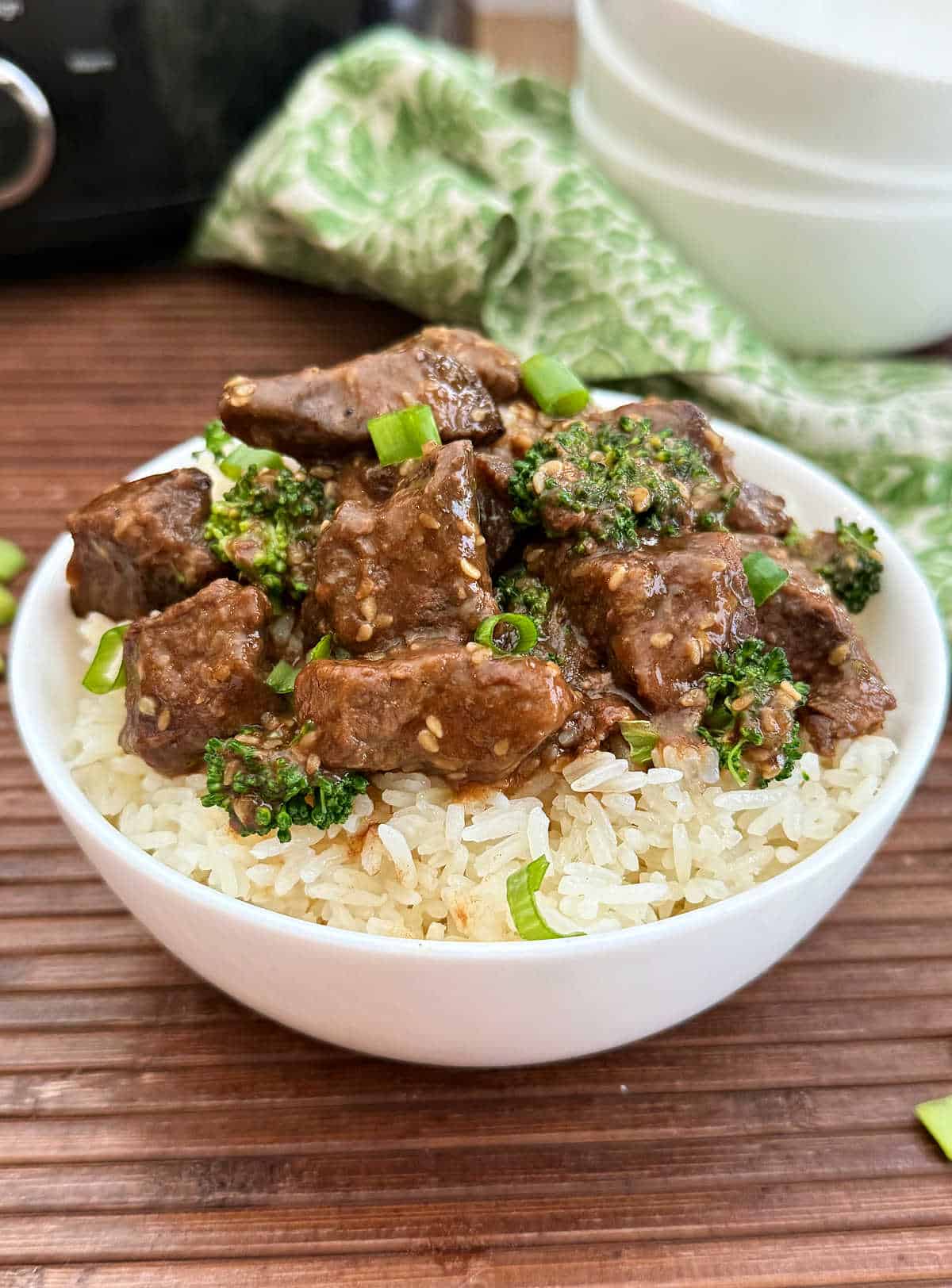 teriyaki beef and broccoli over jasmine rice in white bowl.