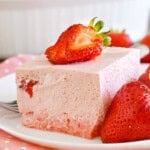 strawberry jello salad on a plate with strawberries.