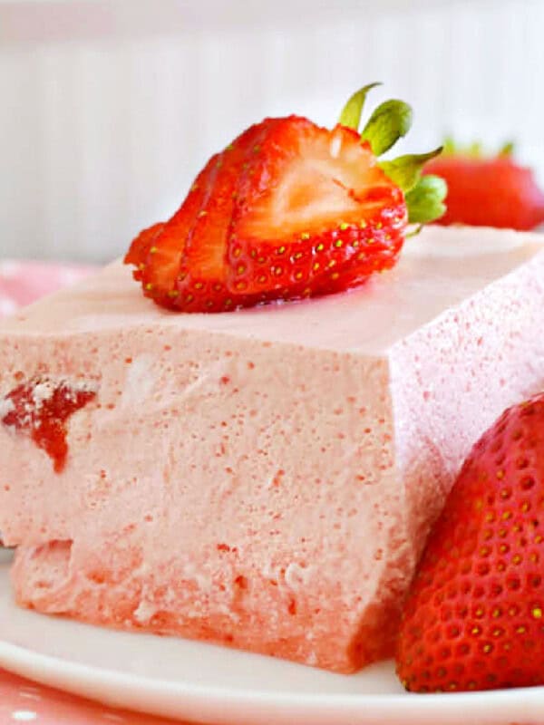 strawberry jello salad on a plate with strawberries.