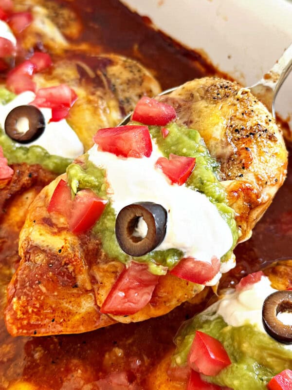 baked chicken breast with enchilada sauce, cheese and toppings on spoon.