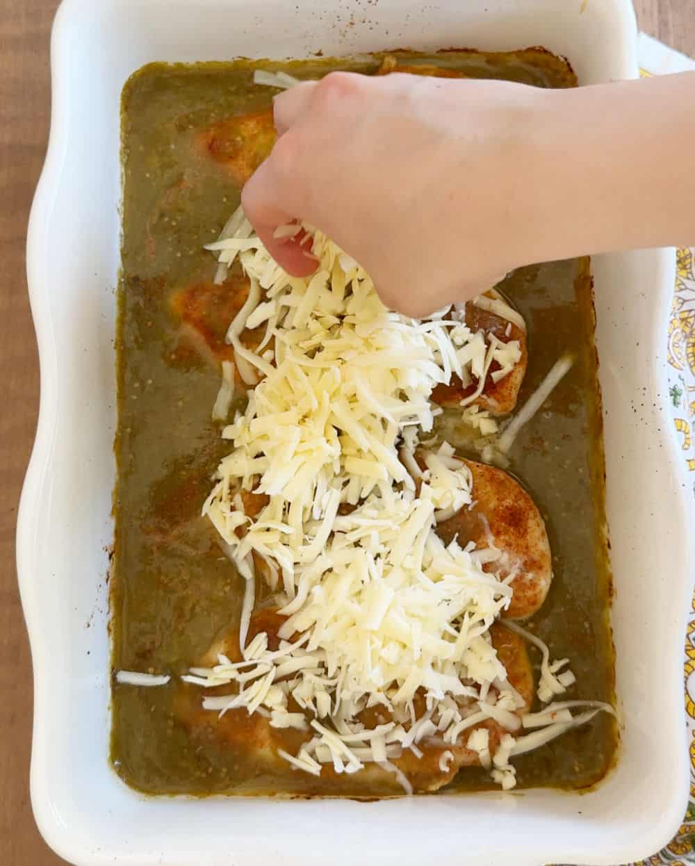 topping chicken with shredded cheese.