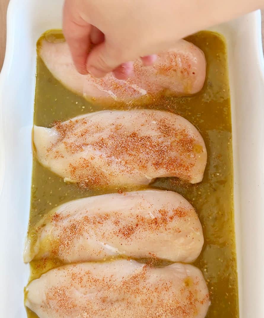 seasoning chicken in baking dish.