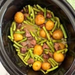 slow cooker garlic butter beef bites and potatoes with green beans in crockpot.