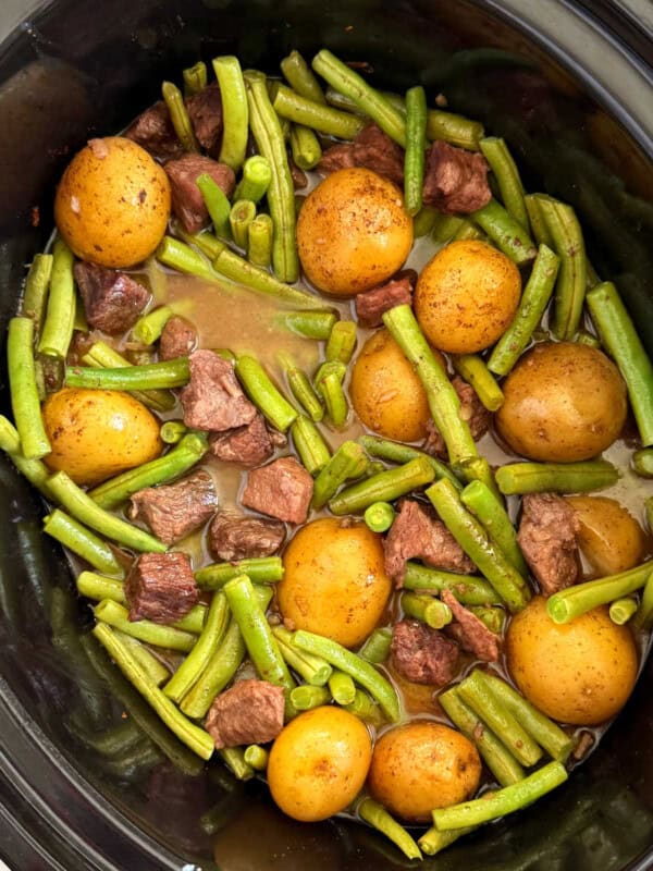 slow cooker garlic butter beef bites and potatoes with green beans in crockpot.