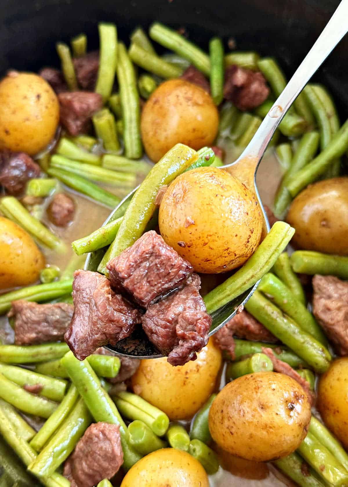 garlic butter beef bites, potatoes and green beans on spoon.