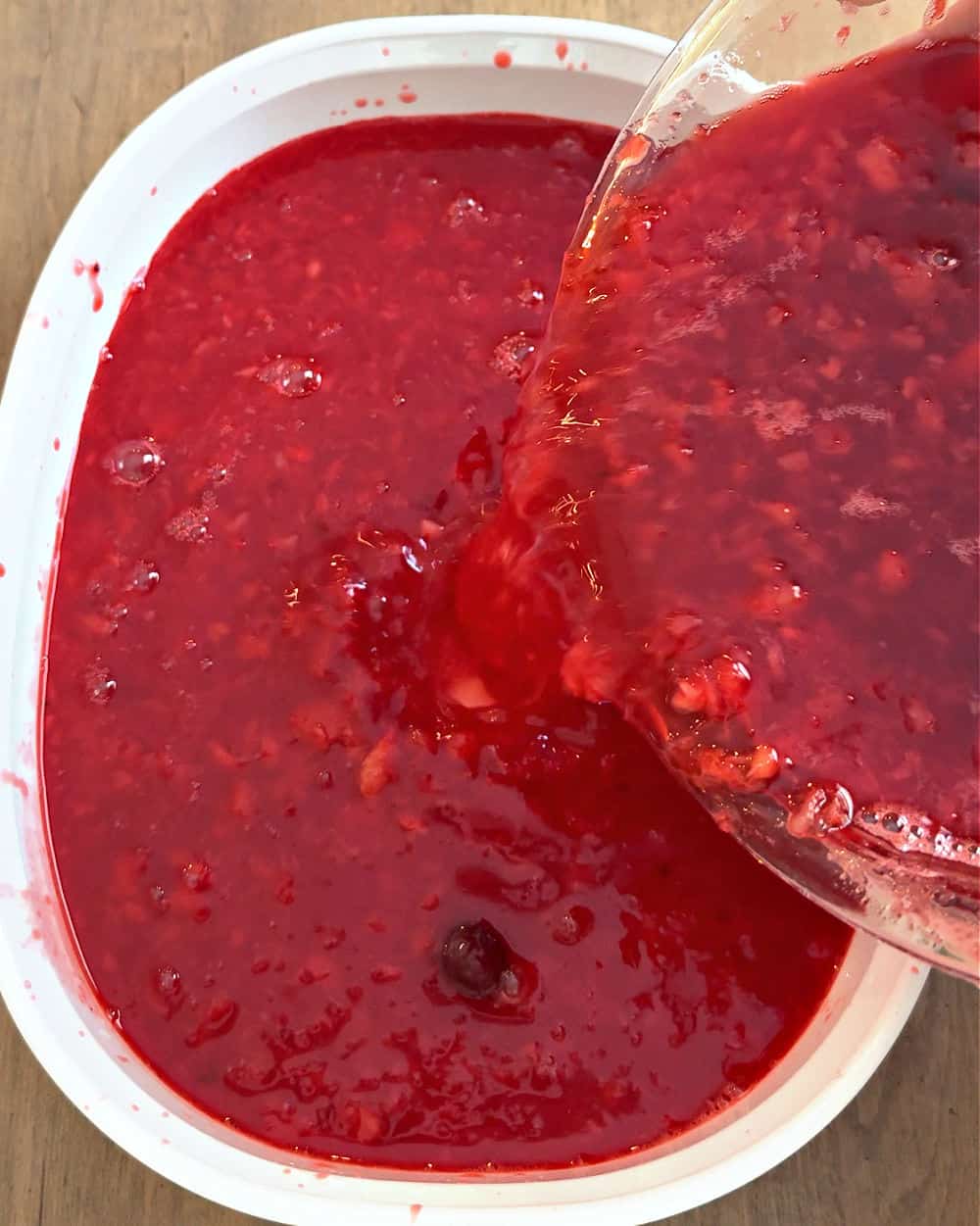 pouring jello mixture into white casserole dish.