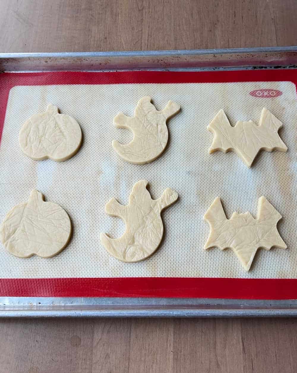 cookie dough cut-out shapes on baking pan.