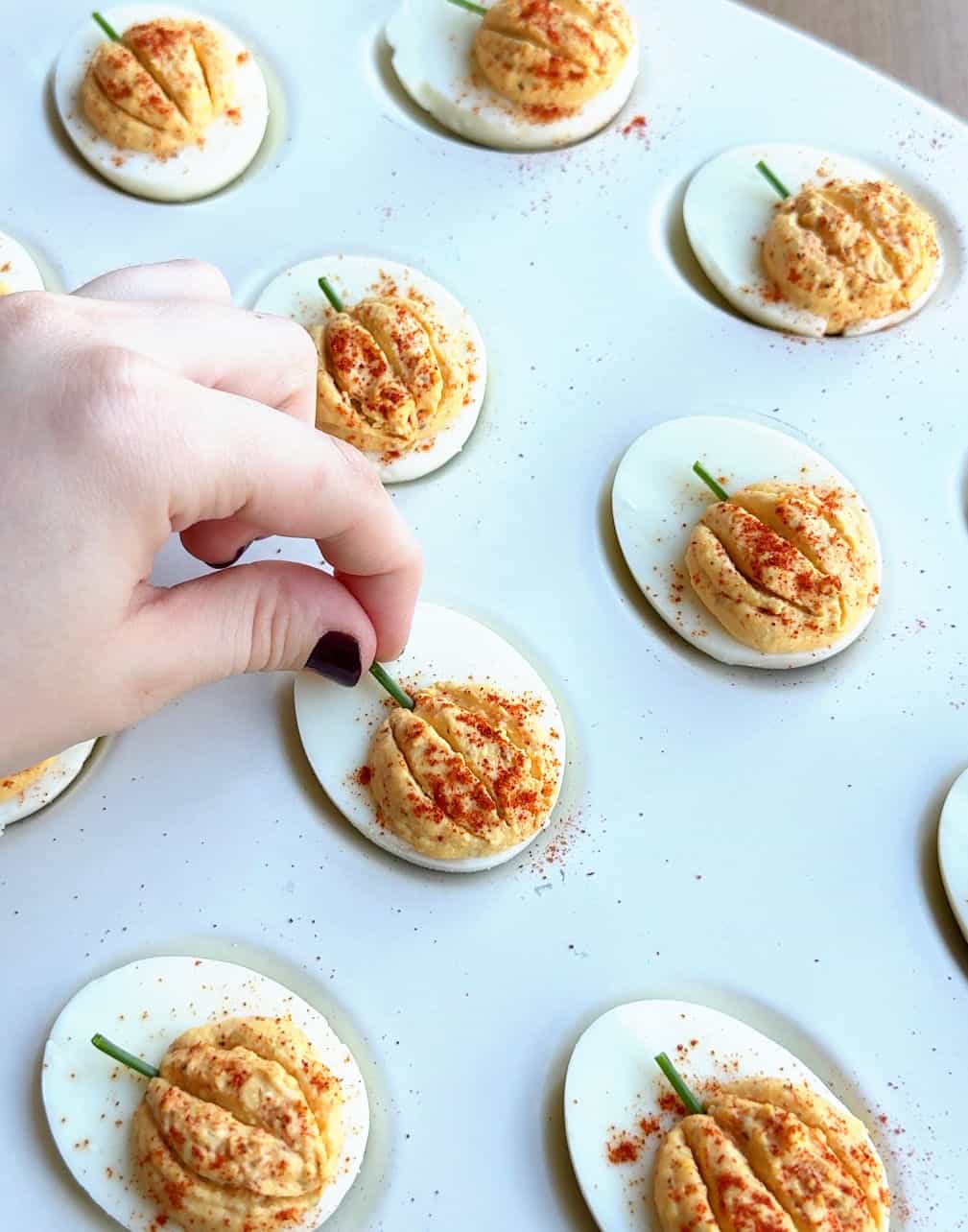 placing chopped chive stem in deviled egg.