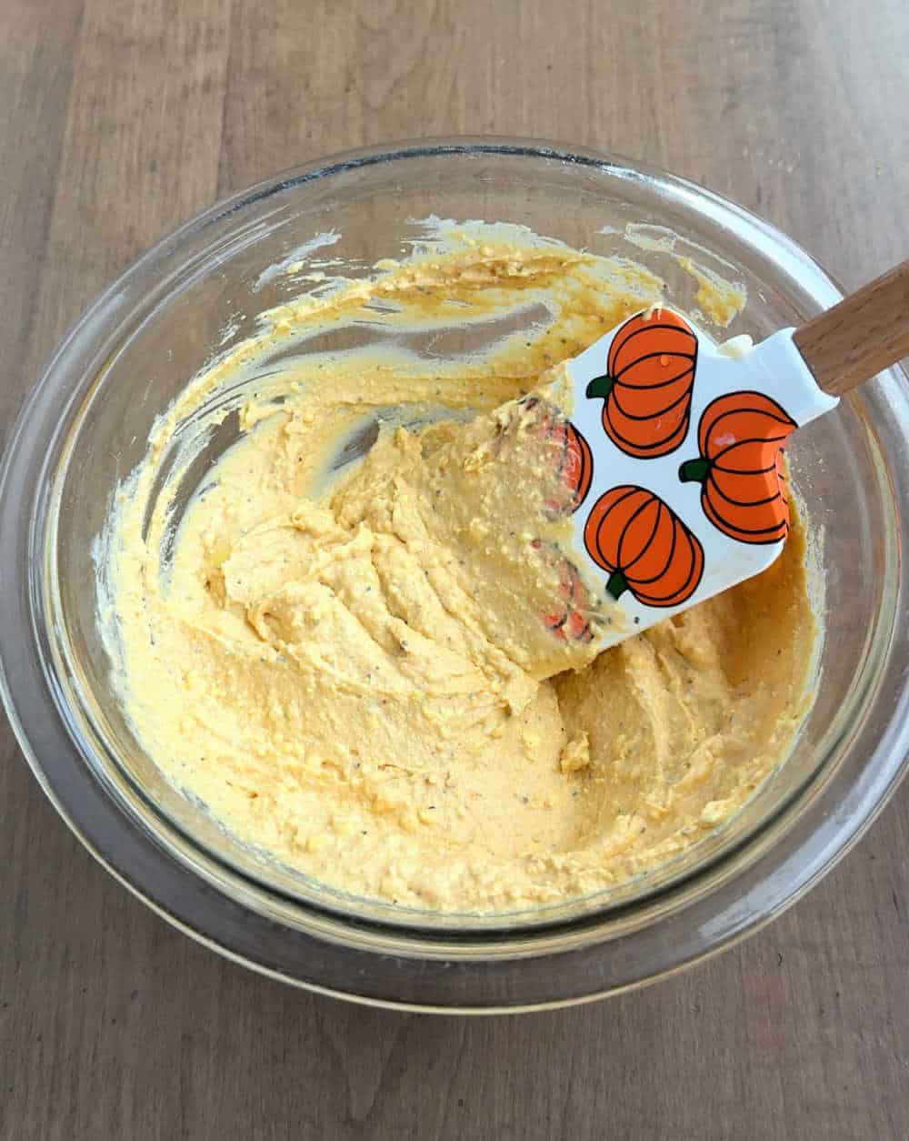 mixing filling ingredients in bowl with pumpkin spatula.