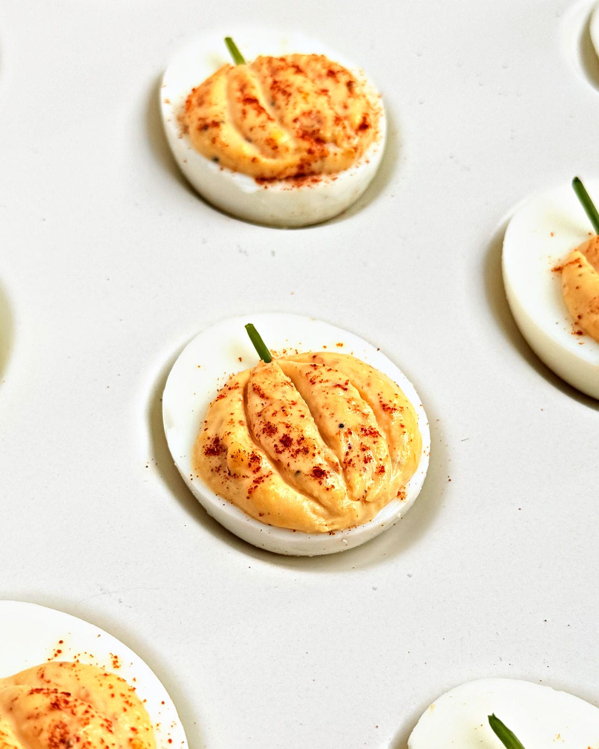 pumpkin deviled egg with paprika and chive stem.