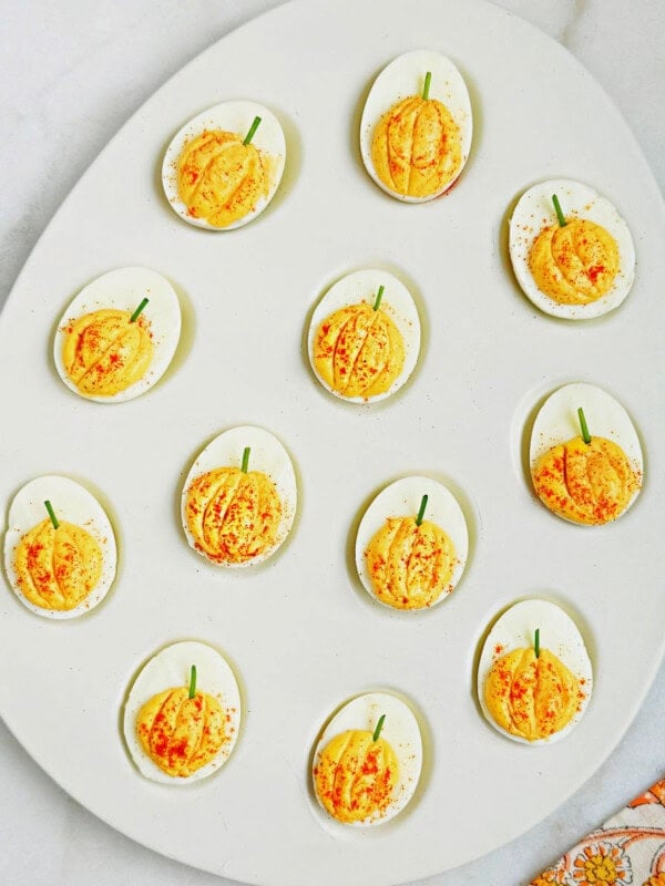 pumpkin deviled eggs in serving dish.