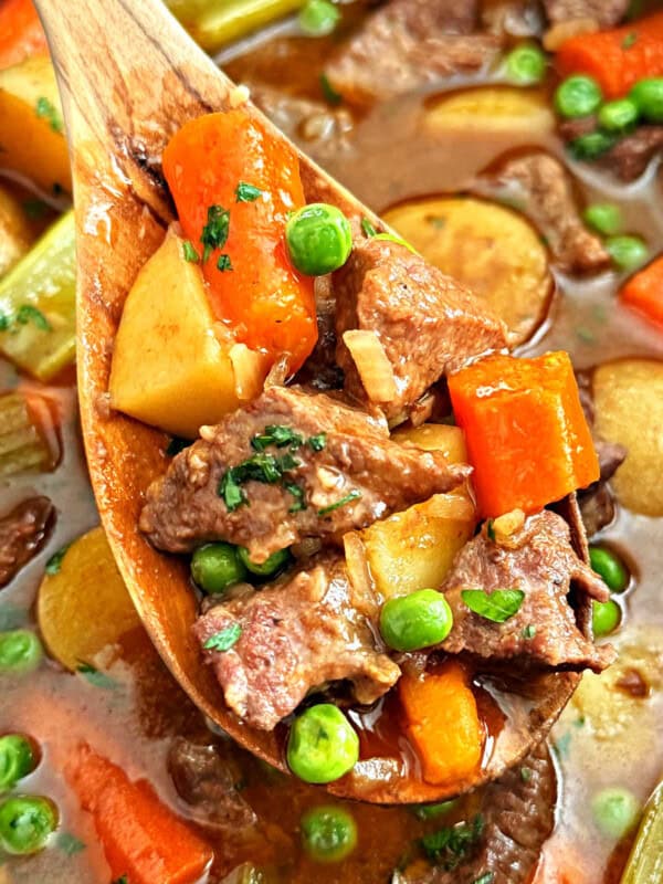 slow cooker beef stew with onion soup mix on wooden spoon.