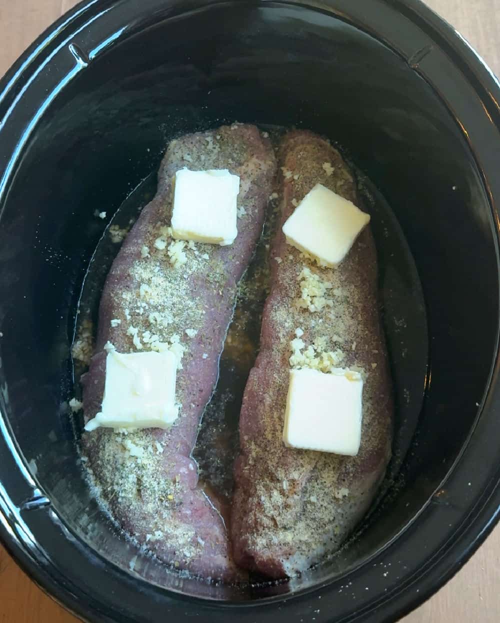 pats of butter on pork in crockpot.