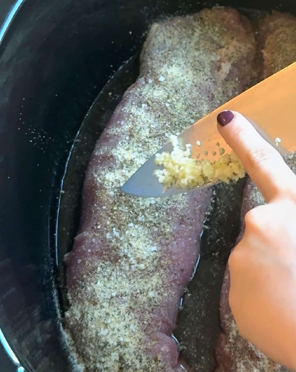 adding minced garlic on meat.