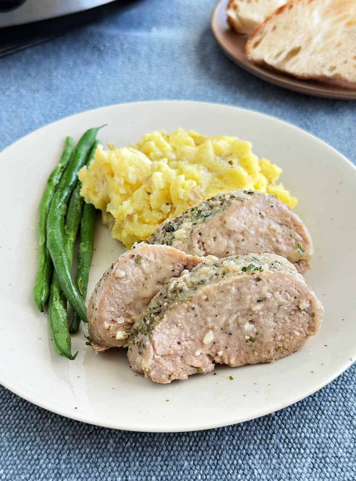 slow cooker garlic butter pork tenderloin with green beans and mashed potatoes on plate.