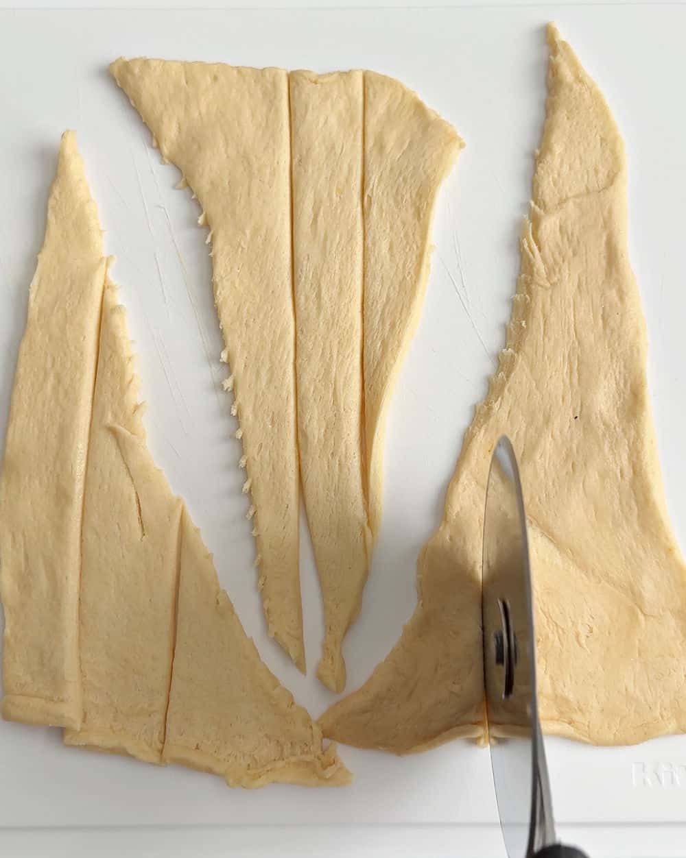 cutting strips of dough with pizza cutter.
