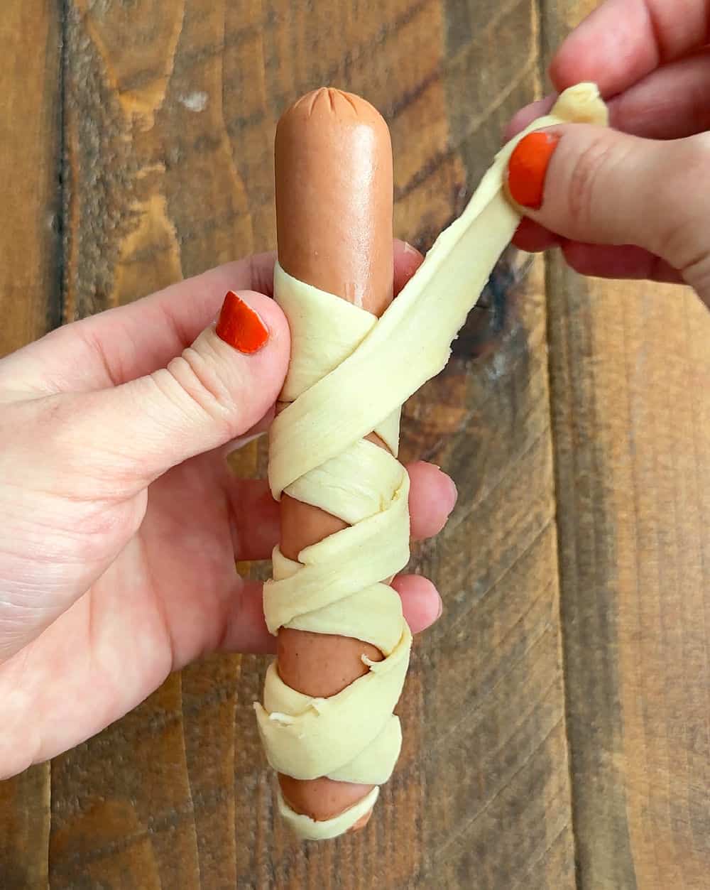 wrapping crescent dough around hot dog.