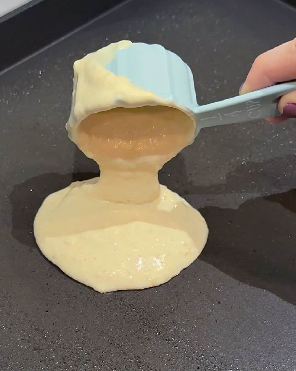 pouring sourdough pancake batter onto griddle.
