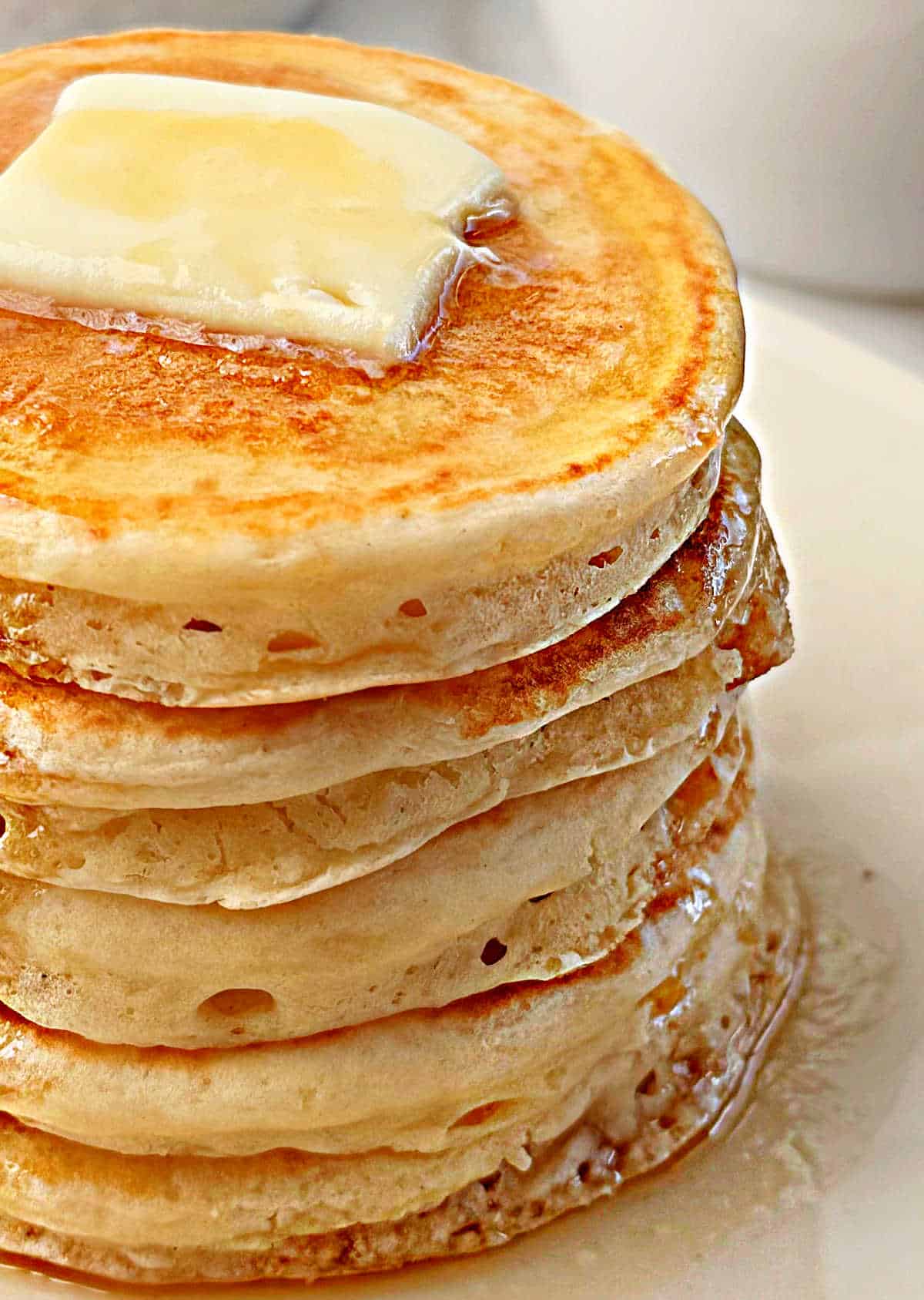 thick and fluffy sourdough pancake stack with butter and syrup.