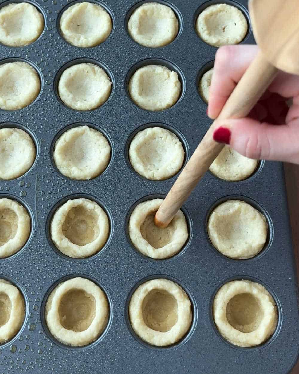 pushing wooden spoon handle into cookies.