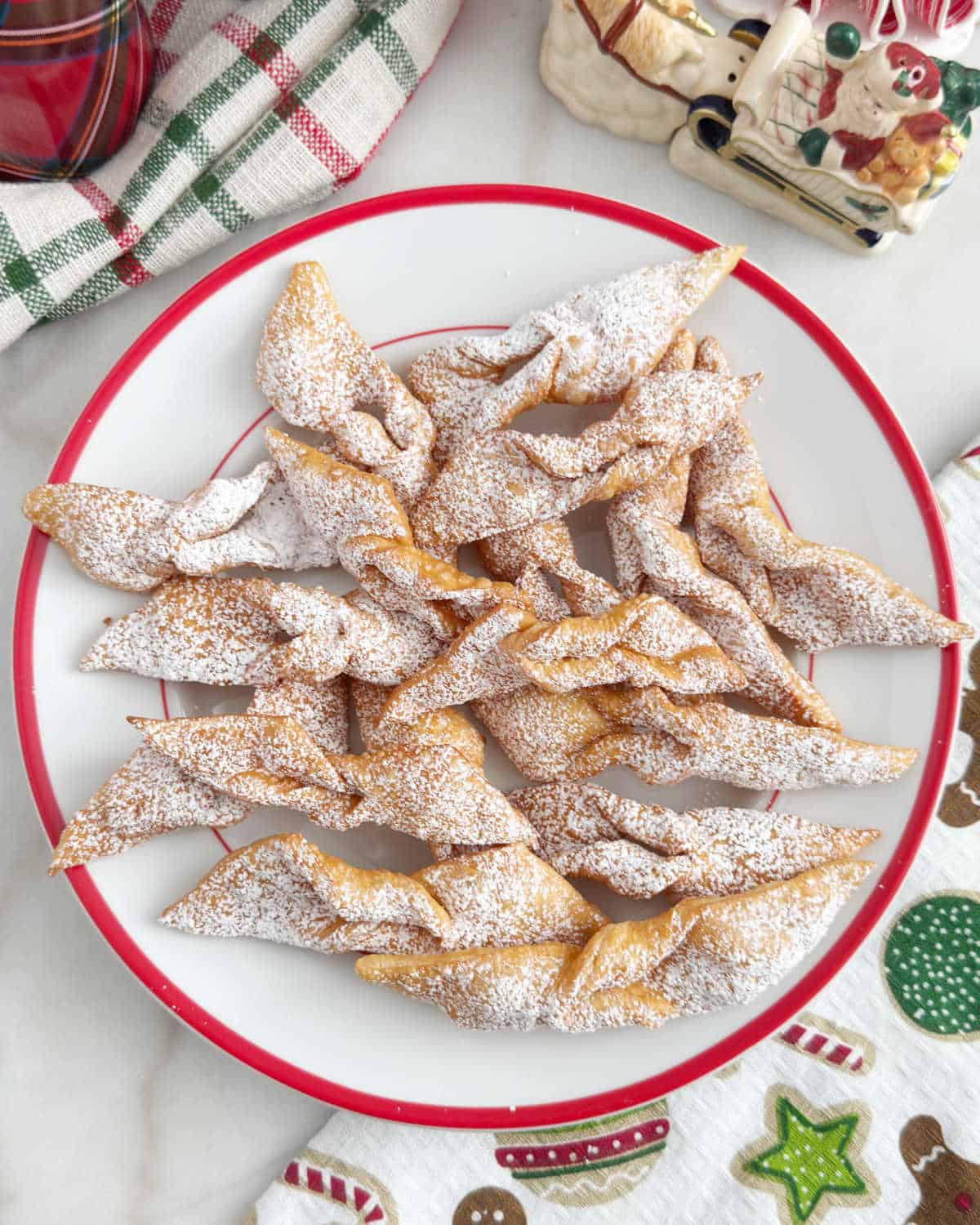 plate of angel wing cookies, cheregi or chrusciki, with powdered sugar.