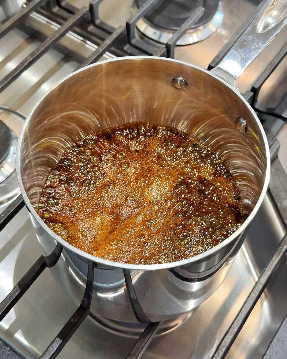 boiling molasses in small pot on stove.