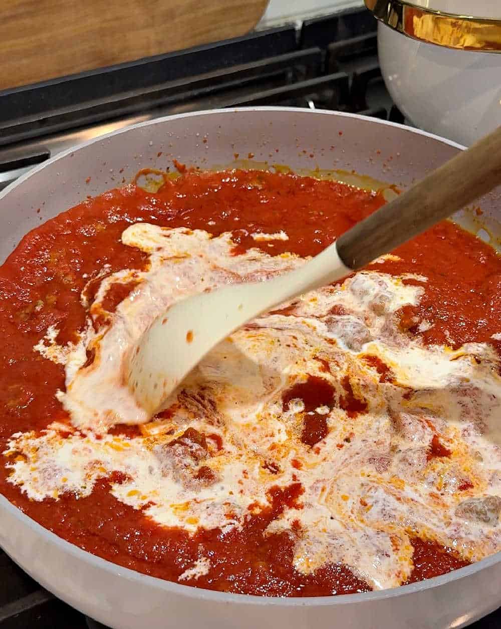 stirring heavy cream into sauce.