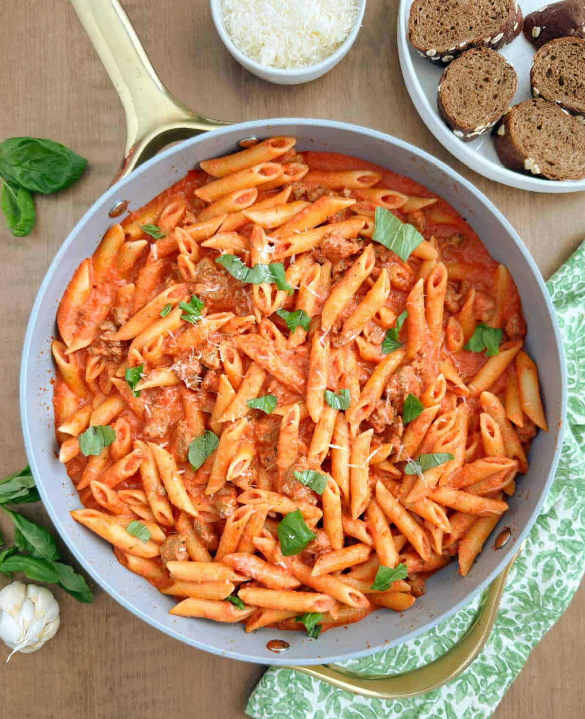 penne alla vodka with Italian sausage and basil leaves on the table.