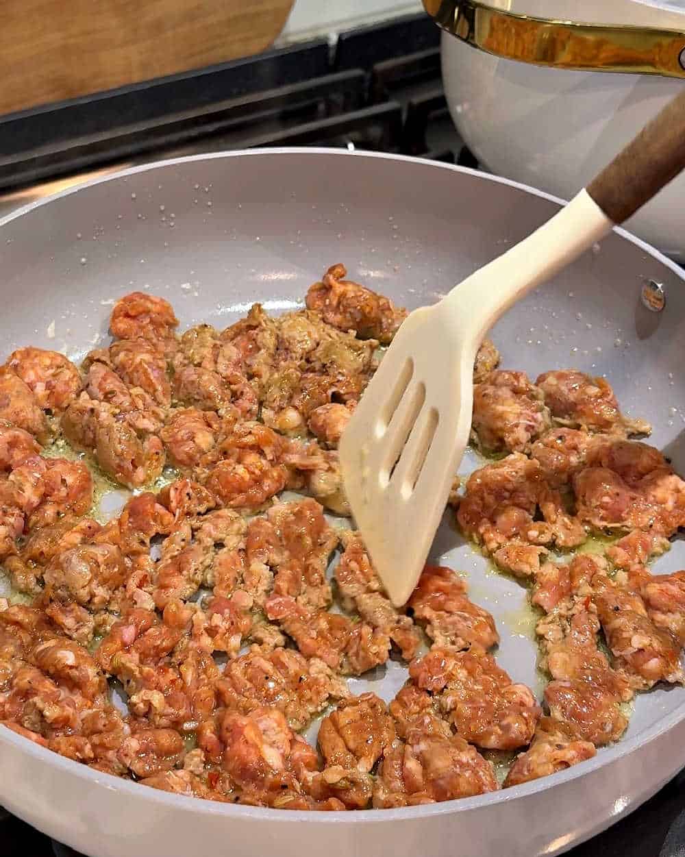 cooking crumbled sausage in pan.