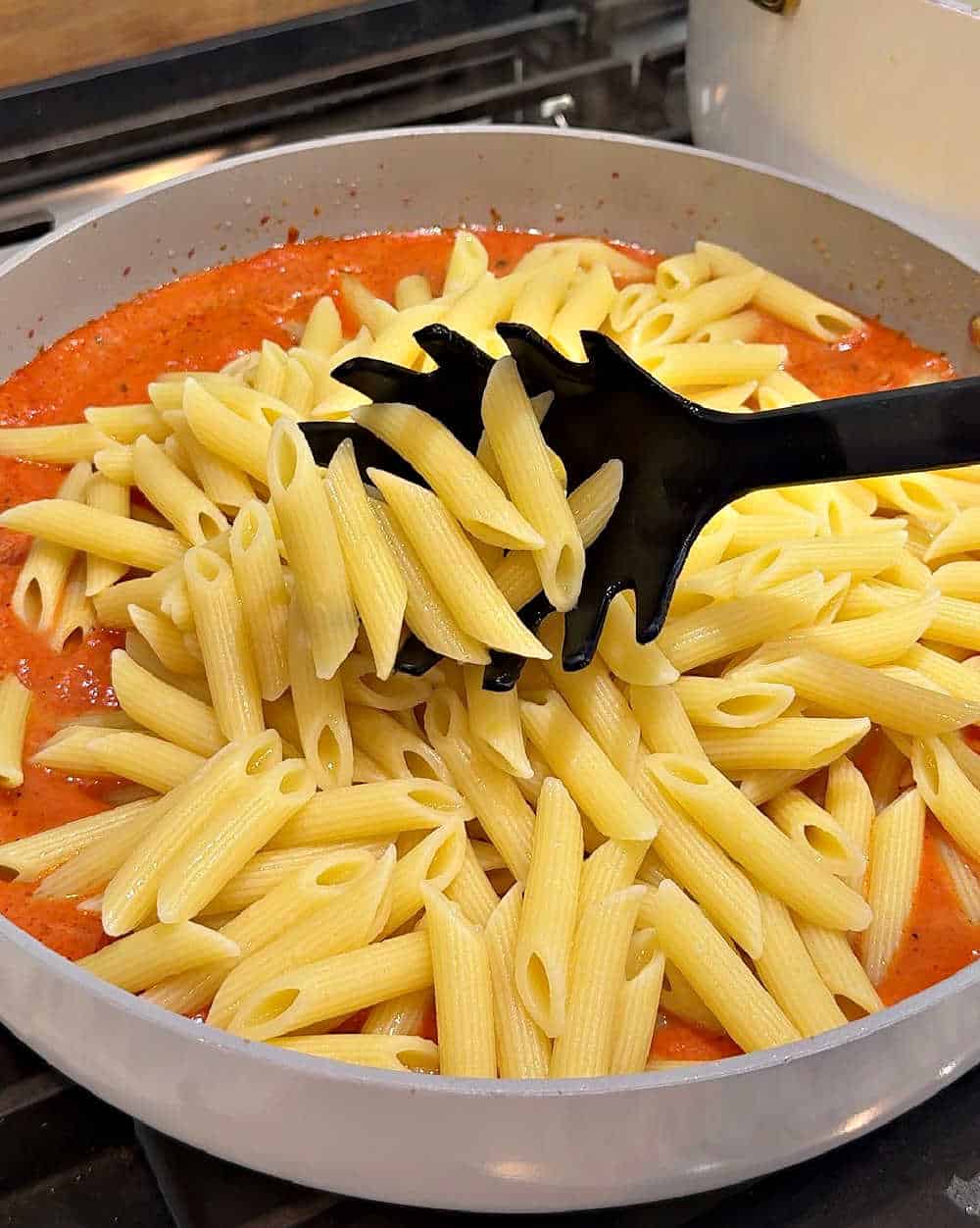 adding pasta to sauce.