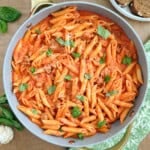 penne alla vodka with sausage and basil in pan.